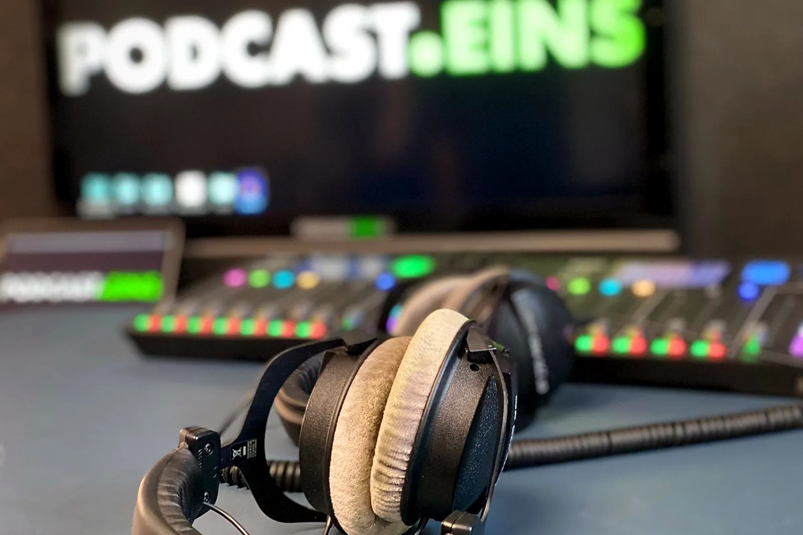 Studiokopfhörer vor dem PODCAST.EINS-Logo