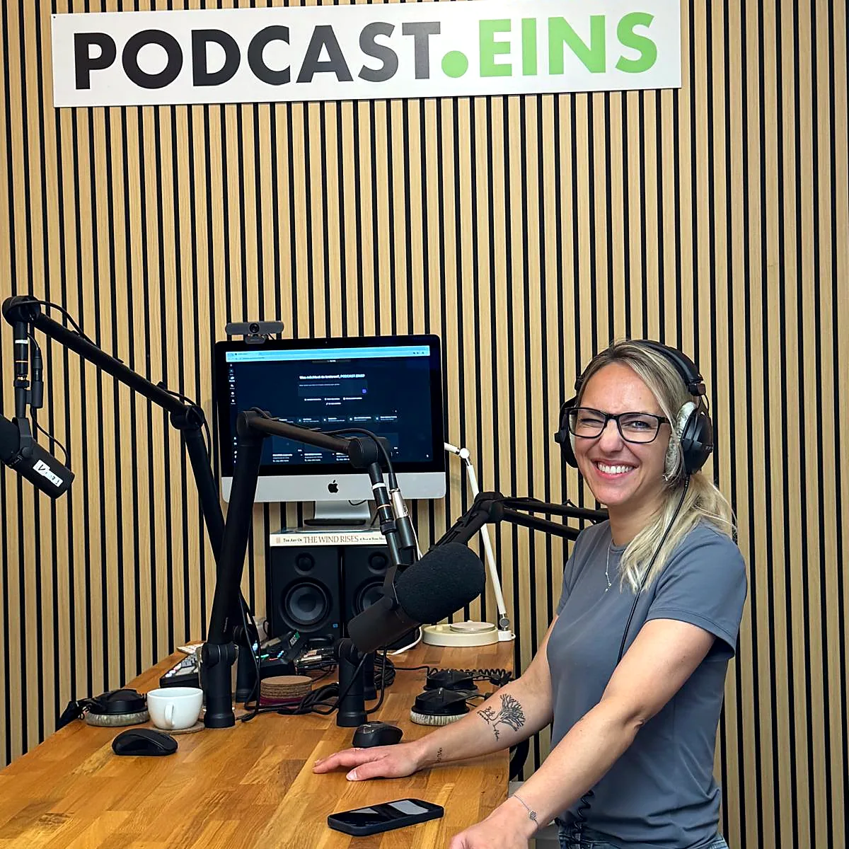 Sprecherin mit Kopfhörern am Mikrofon im Studio von PODCAST.EINS